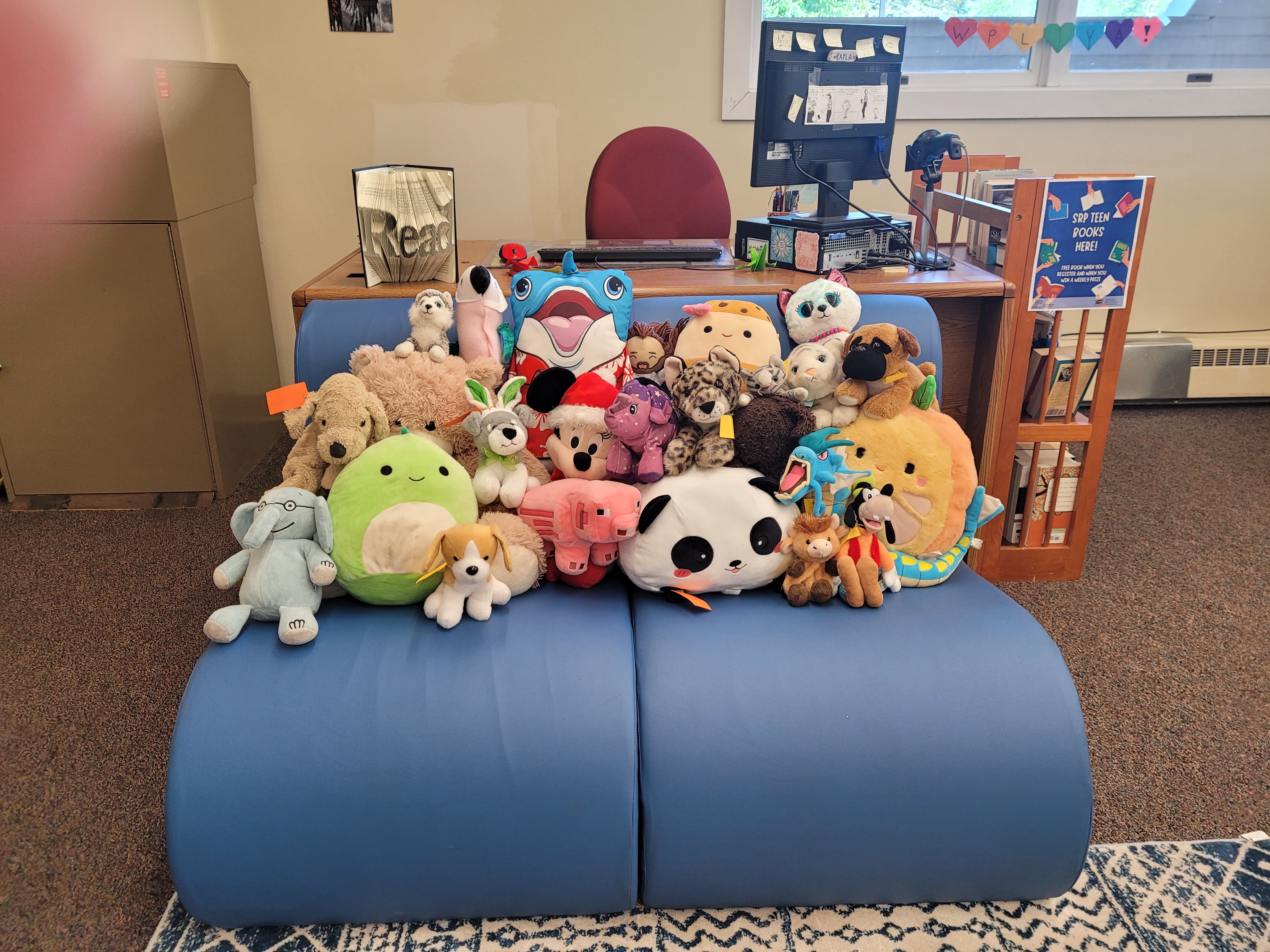 Group picture of stuffed animals on comfy blue chairs at Wells Public Library