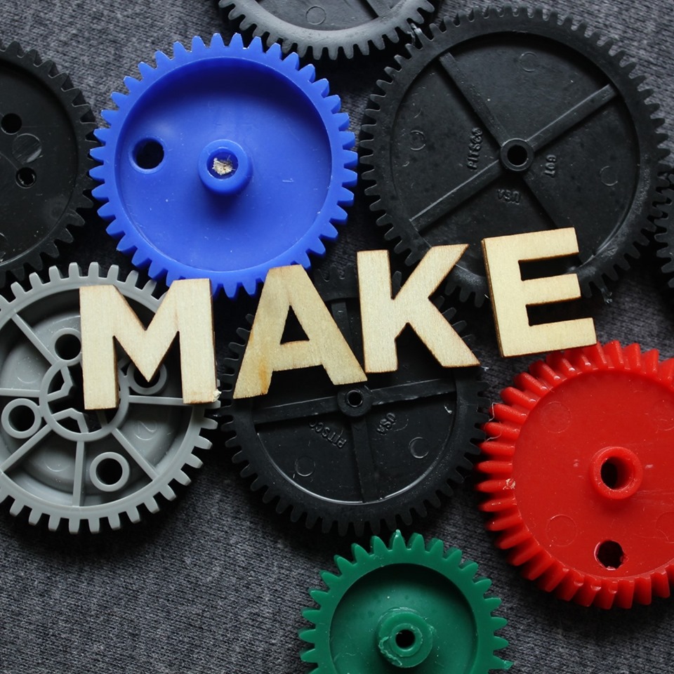 multiple plastic gears with the word MAKE spelled out with wooden letters