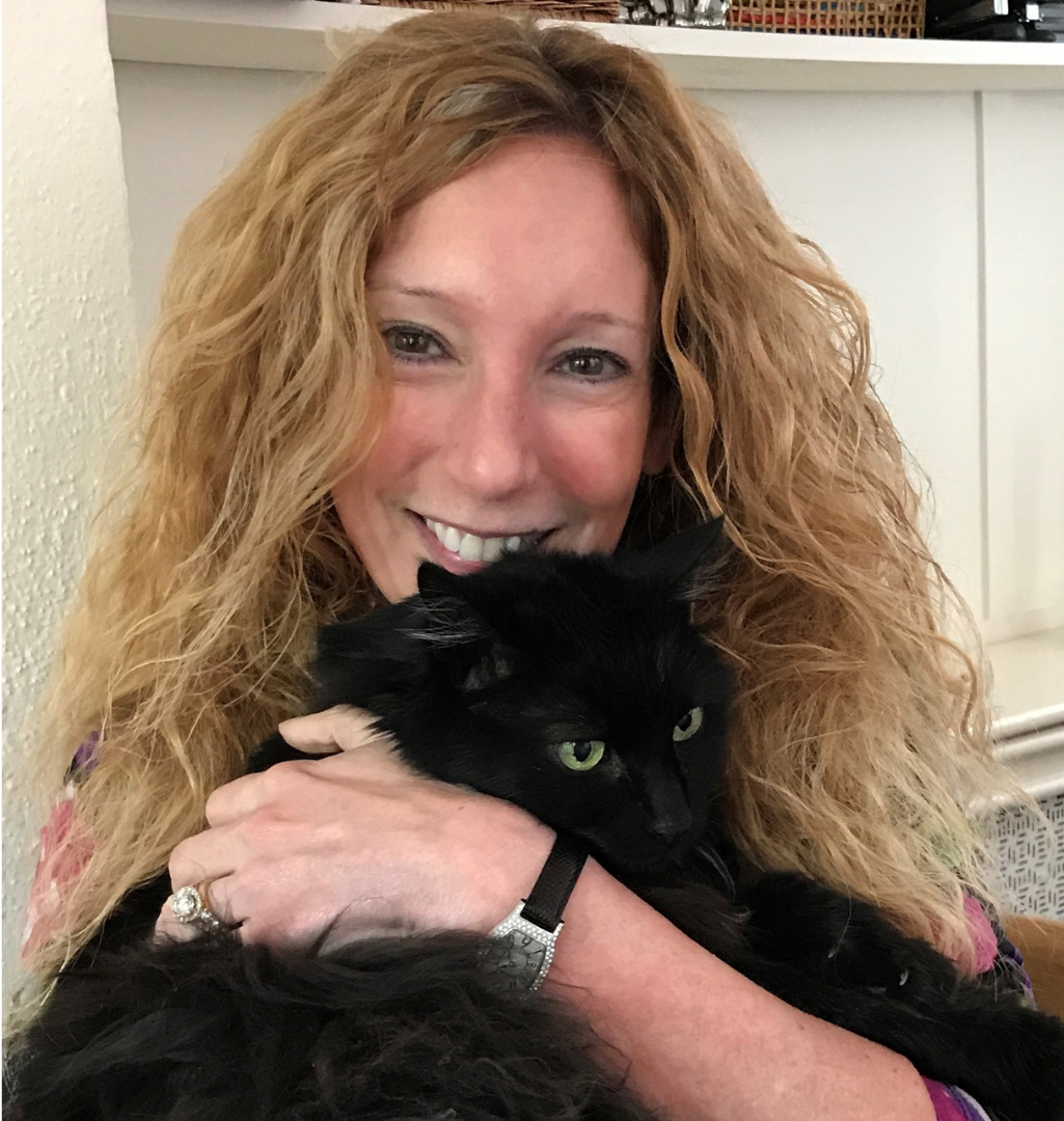 Rachel Geller, a smiling woman with blond hair, holding a black cat