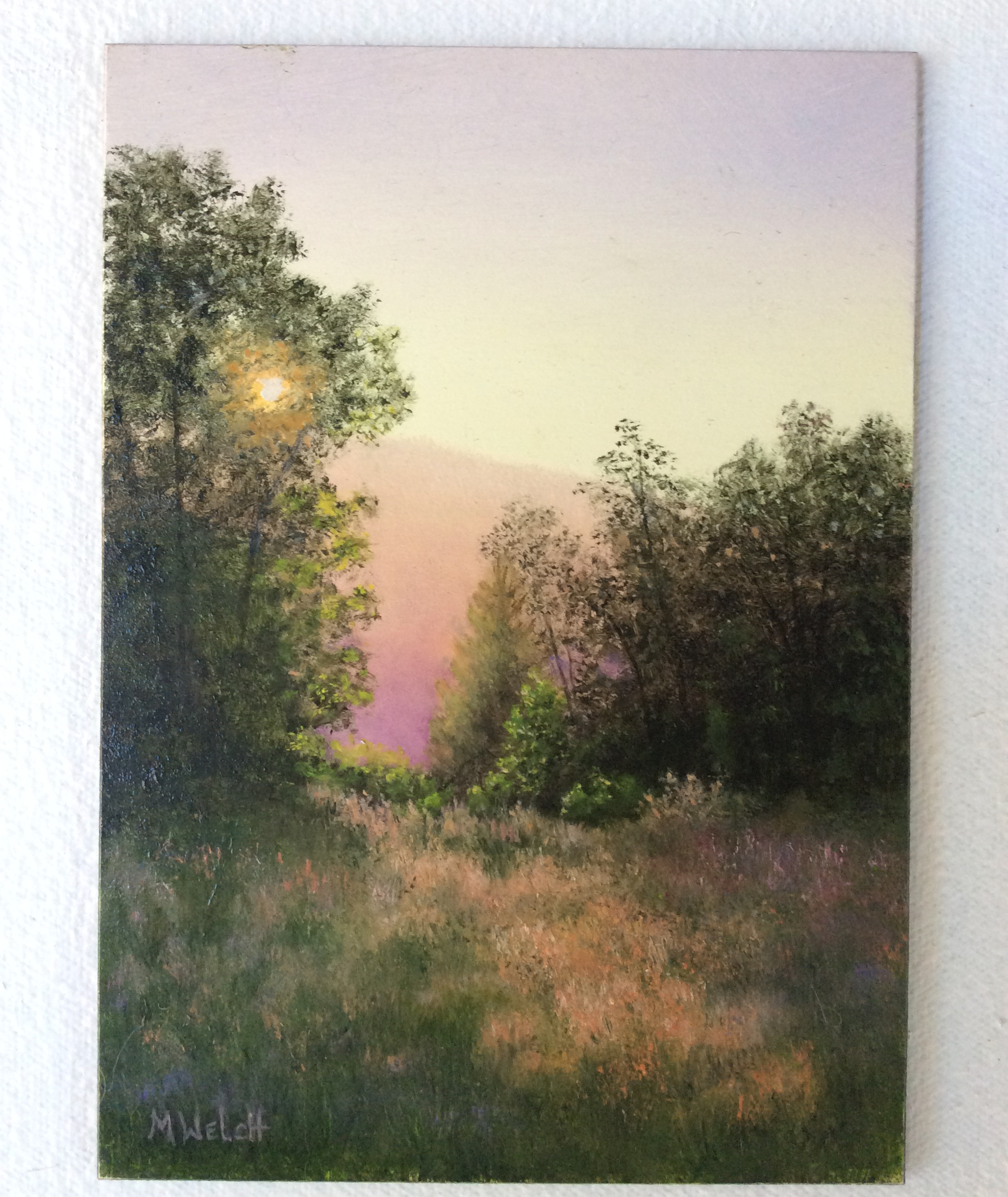A painting of meadow grass and trees, with a low sun shining through over the horizon.