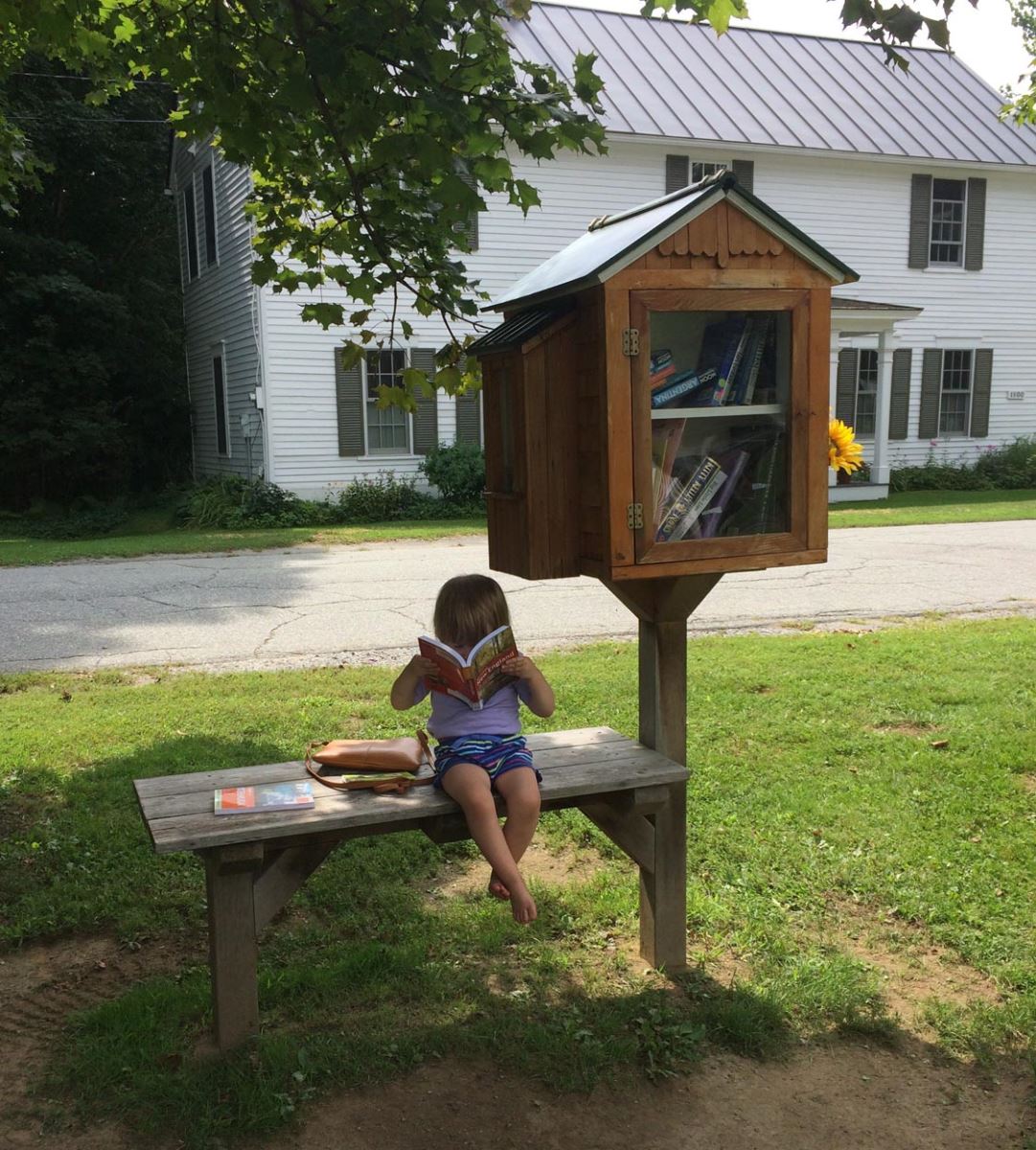 Photo of child reading next to the Little Free Library at the Converse Library in Lyme NH