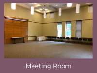 Picture of the Meeting Room with 8 tables, several chairs and projector screen.