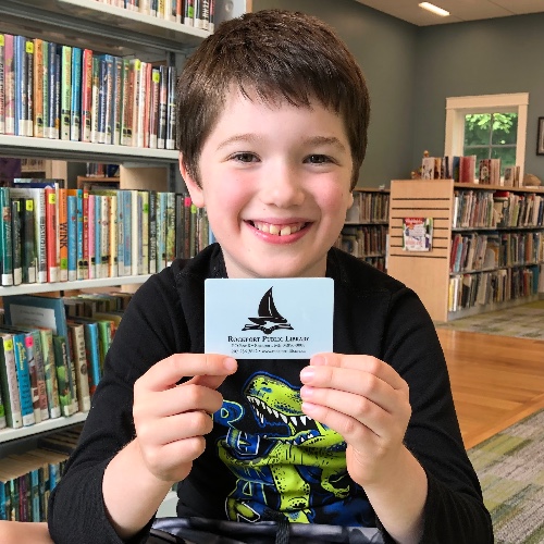 Picture of male child holding a library card and smiling
