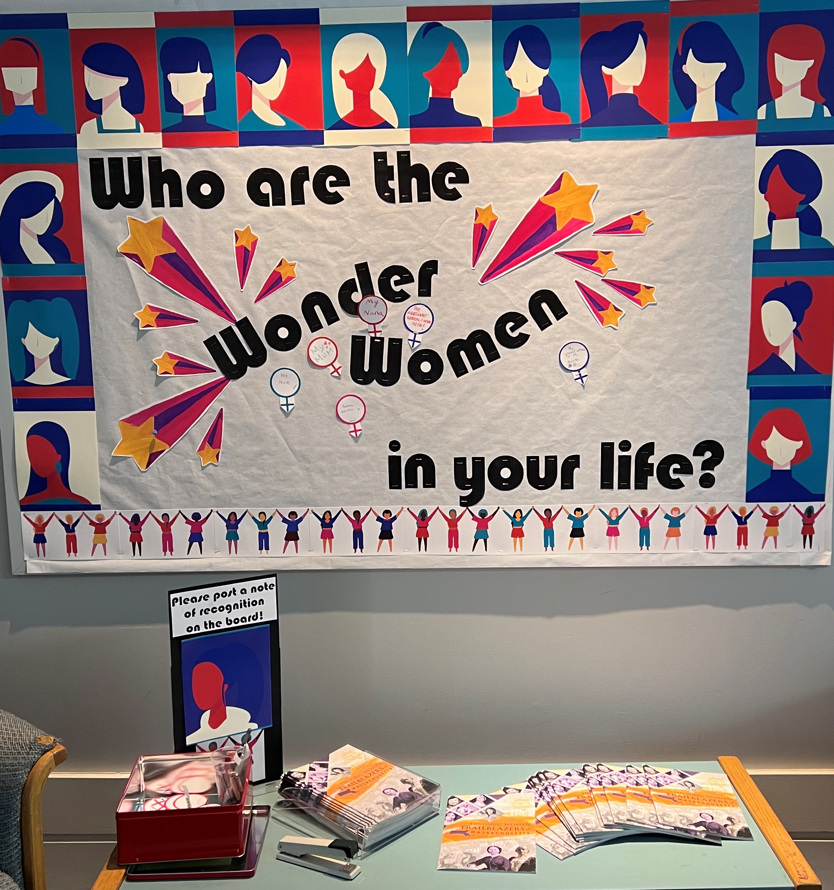 colorful photo of bulletin board with graphics representing silhouettes of women's heads